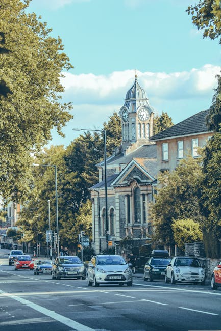 A street scene outside The Rookwood Village, a multi-storey brick building with decorative black and white timber framing, situated on a busy urban road in Bounds Green. The building's ground floor fe